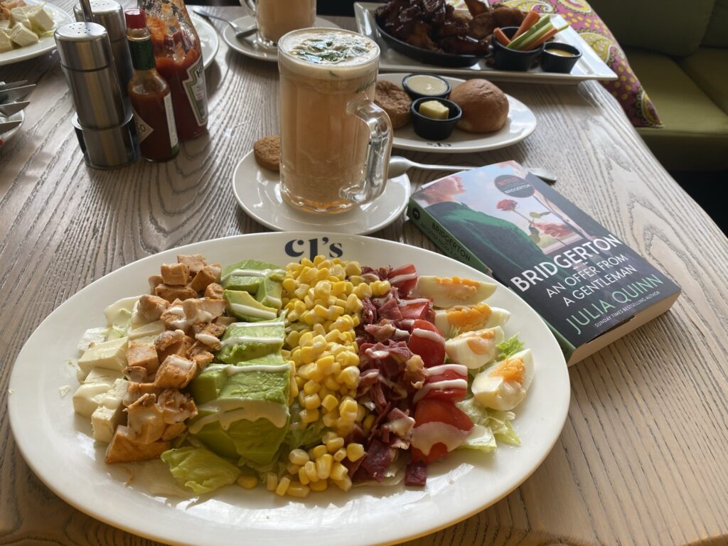 Salad plate and a cup of glass tea besides An Offer from a Gentleman by Julia Quinn