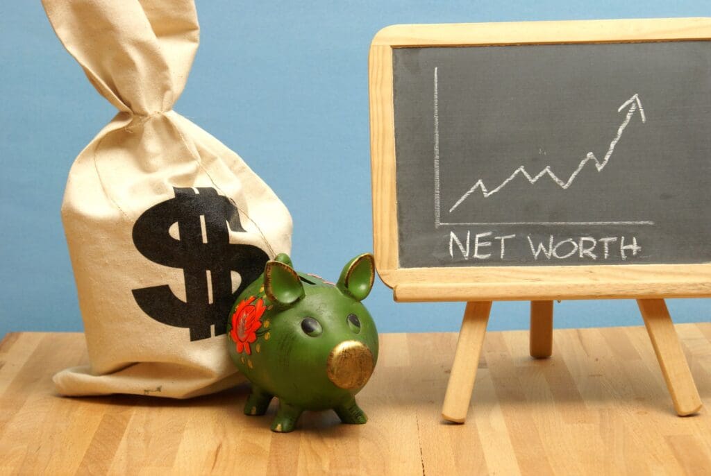 Black board showing Personal Net Worth writing with a piggy bank and carry bag with $ sign next to it