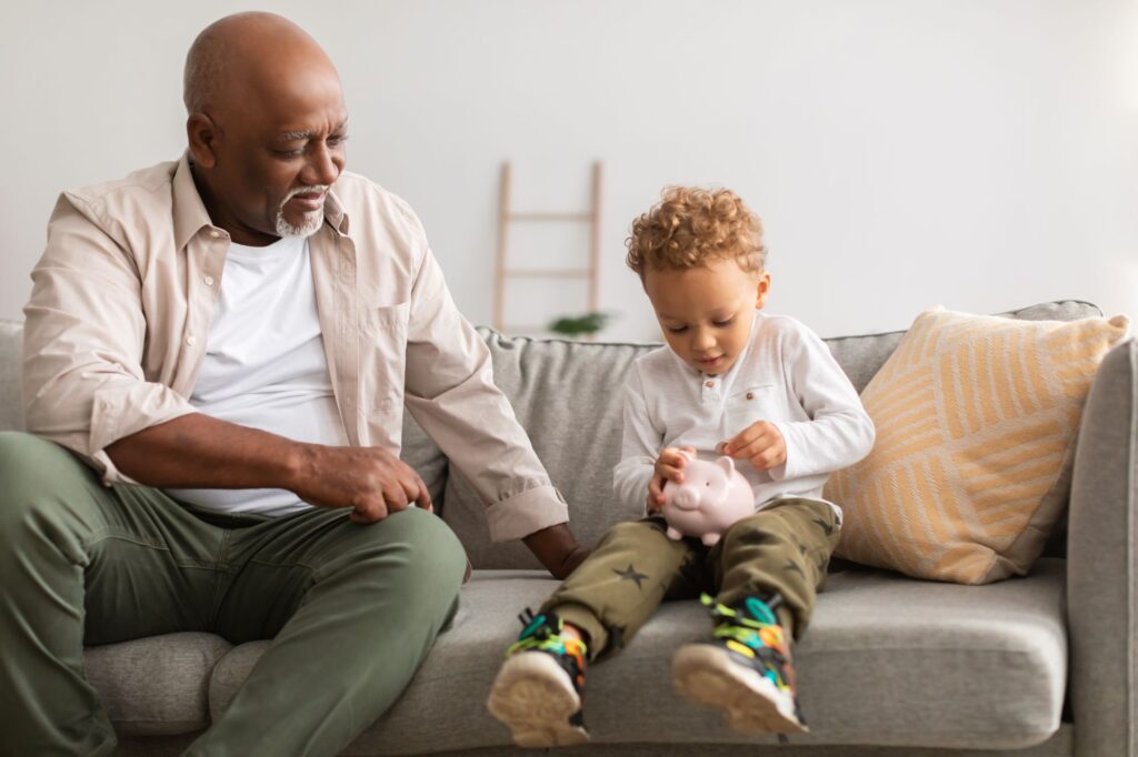 african-american-grandpa-and-grandson-putting-money-in piggy bank