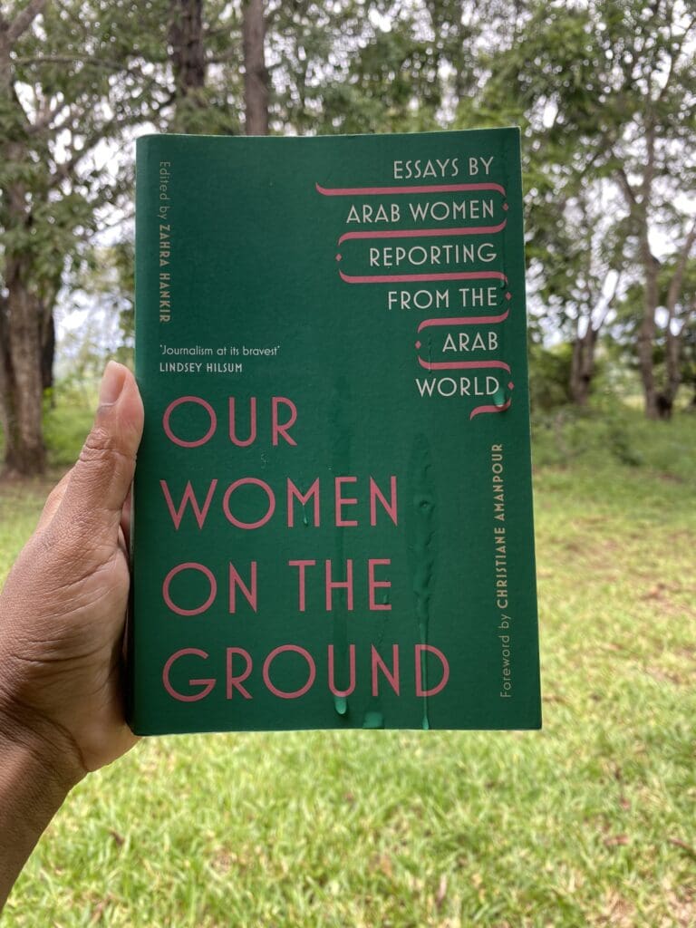 holding a copy of Our Women on the Ground