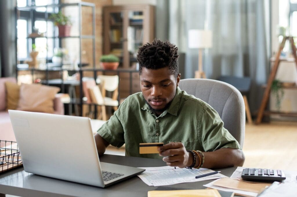 Young African businessman looking at credit card in his hand