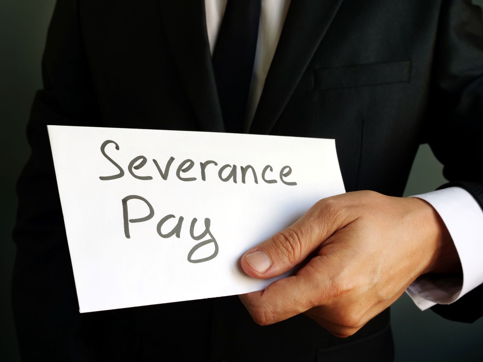 A male hand holding a paper sign of severance package