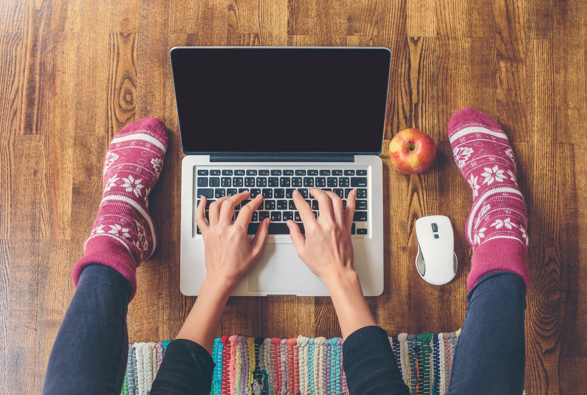 a photo showing someone working in pink socks with white pattern, on an open laptop, sitting on the floor - working on freelance jobs
