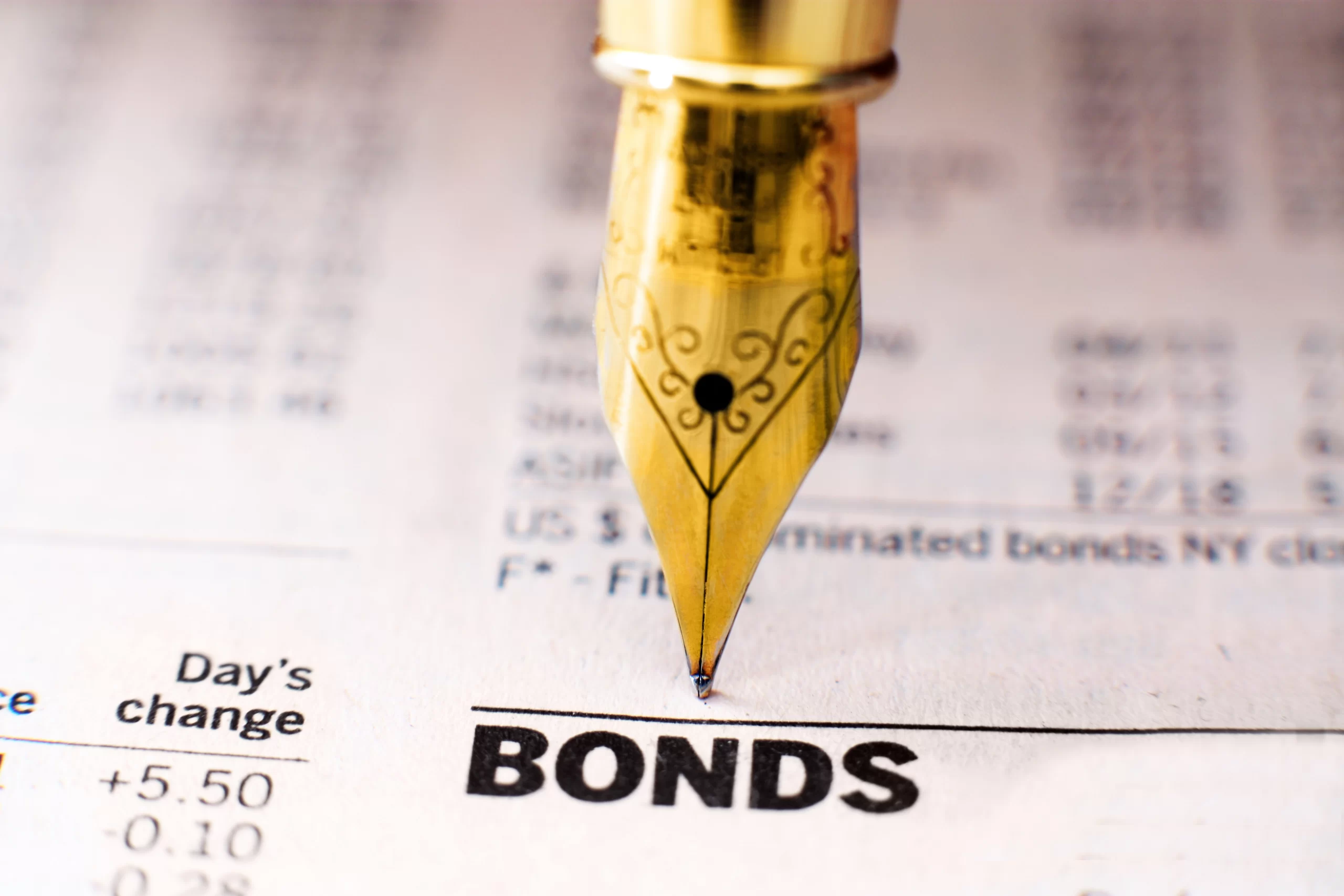 A gold pen on a paper with bolded BOND word indicating investing in bonds