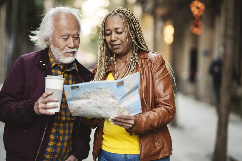 multiracial senior couple traveling in the city with a map - retire abroad