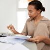 Young Black woman doing finances at home and using calculator - using the Rule of 72 for investment planning