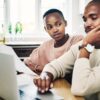 Shot of a young couple looking stressed while going over their finances on a laptop at home-Financial Goal Setting for Couples
