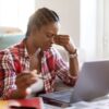Stressed black woman sitting in front of laptop-Behavioural Biases Affecting Your Finances