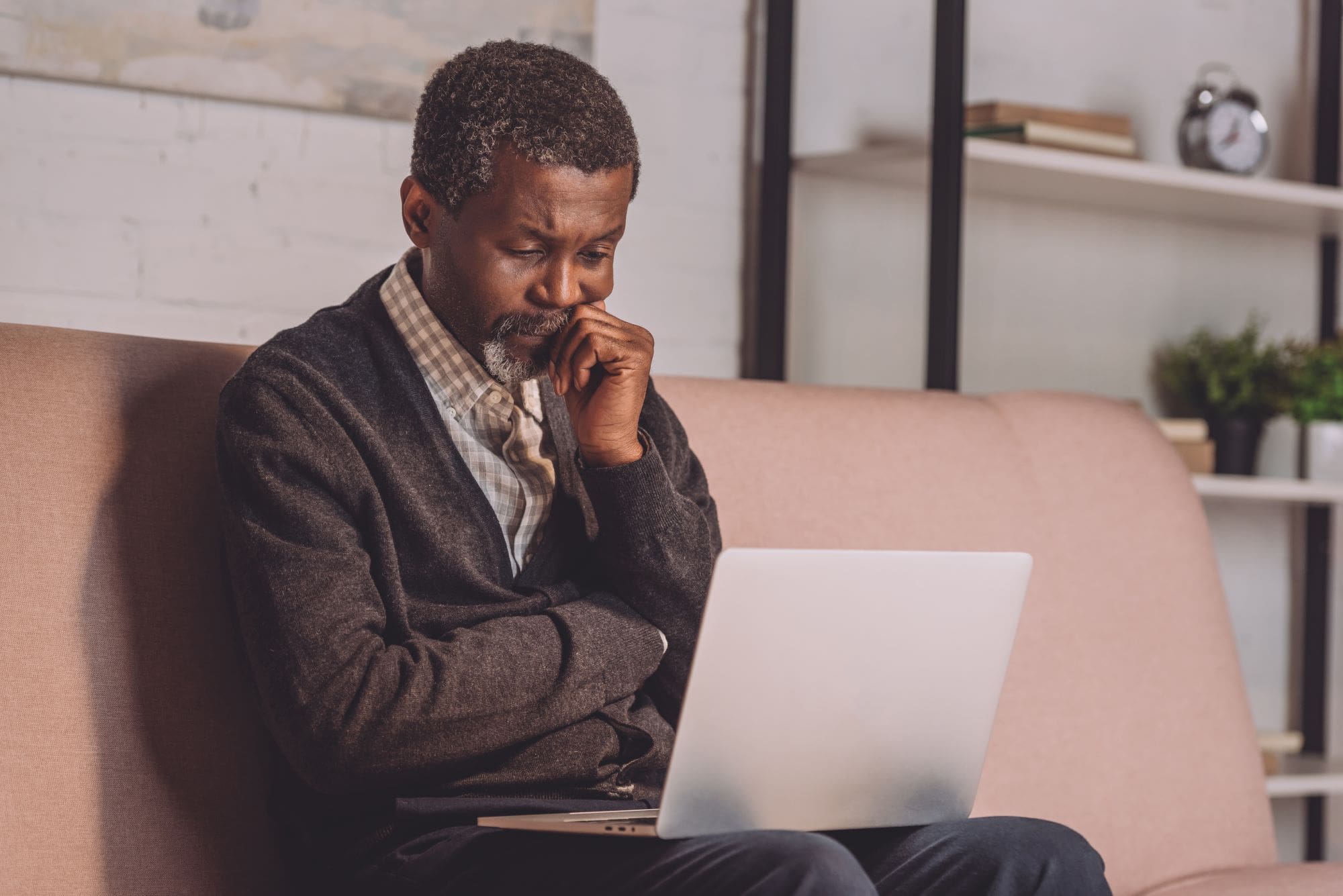 upset african american man looking at laptop while sitting on sofa-Is my money safe in a money market fund?