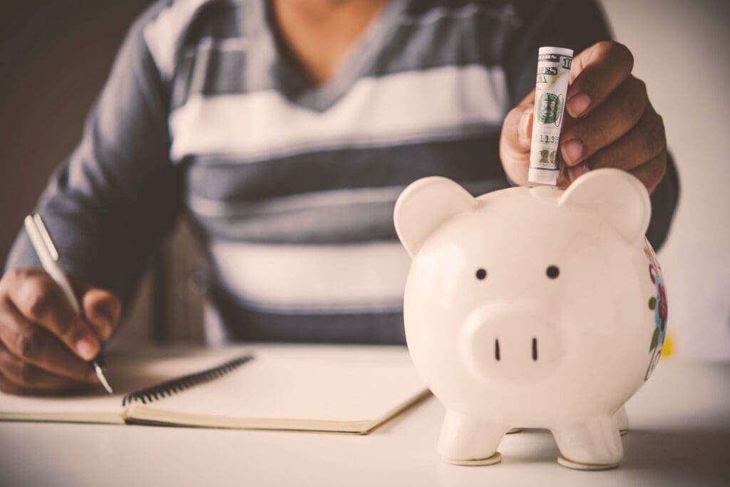Hands of a young African putting money into a piggy bank